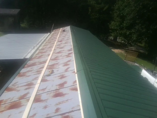 Old rusted panels beside newly installed green metal roofing — Wind Damage Roof Repair by Roofing Brothers in Ontario