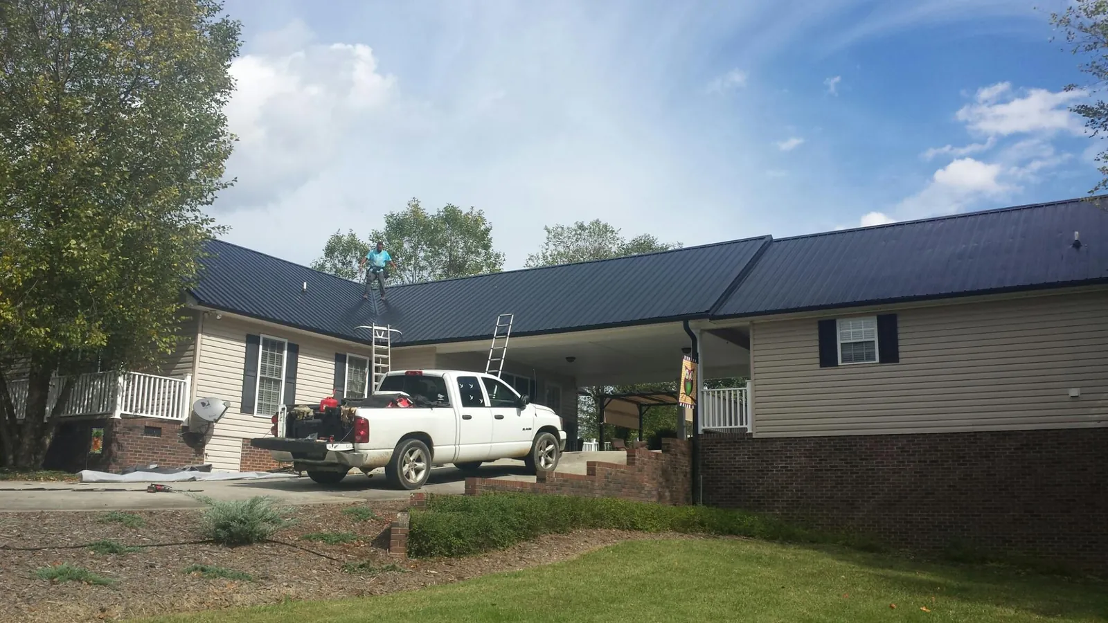 Black metal roof over a home and attached breezeway with ladders set in Ontario