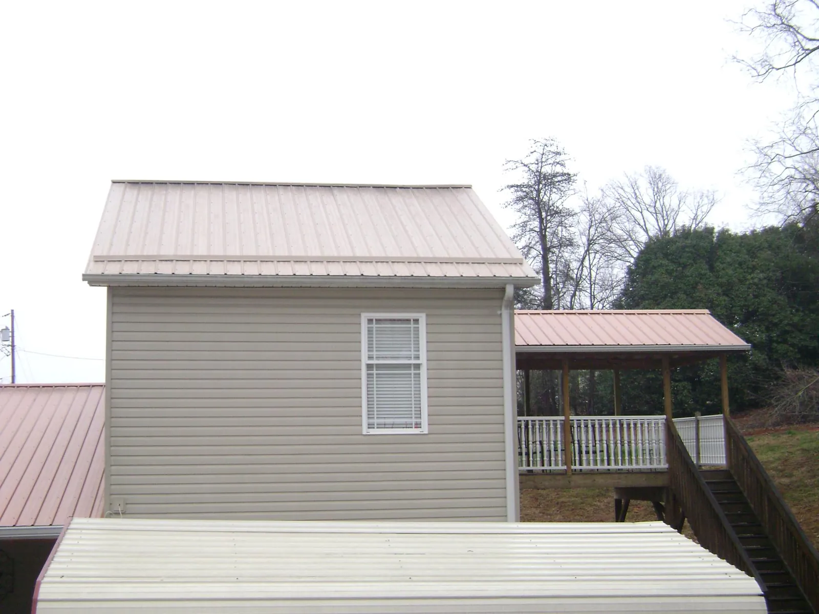 Tan metal roofs on a two story addition and attached porch, from a Roof Replacement job in Ontario
